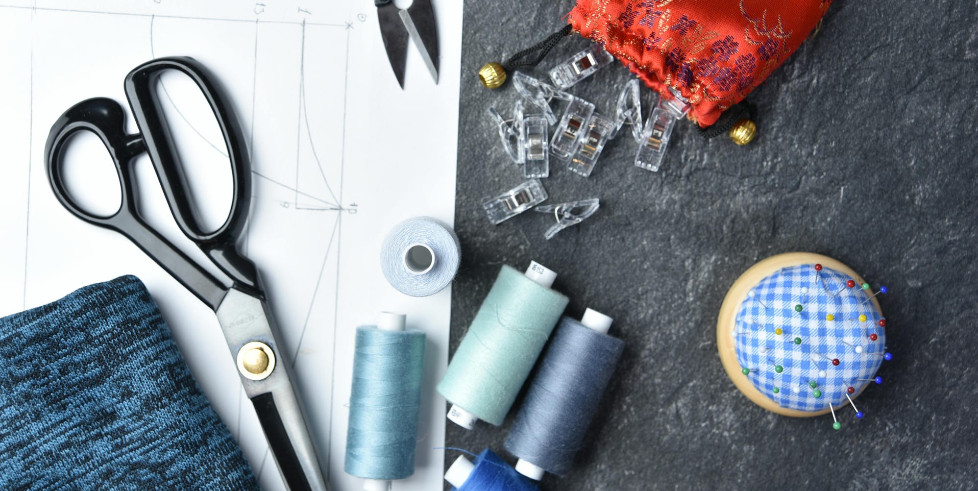 Flat lay of sewing supplies and tools, featuring threads, scissors, and fabric.